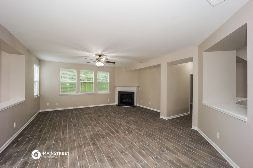 an empty living room with a fireplace and a ceiling fan