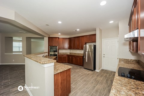 a kitchen with granite counter tops and a stainless steel refrigerator