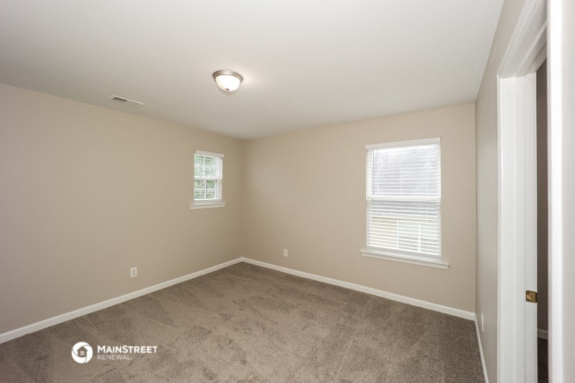 a large room with carpet and two windows