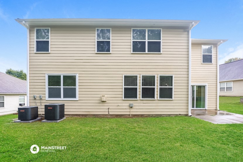a yellow house with a green lawn and two air conditioning units