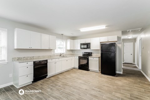 a kitchen with white cabinets and a black refrigerator