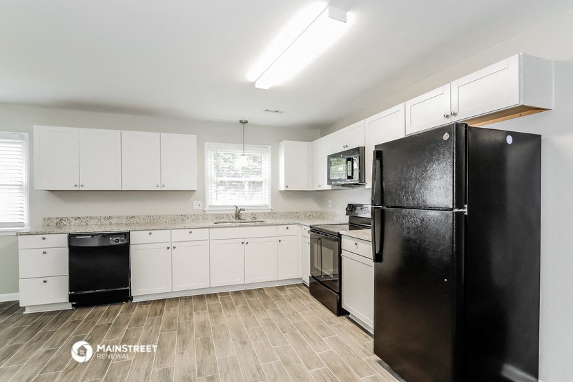 a kitchen with white cabinets and a black refrigerator