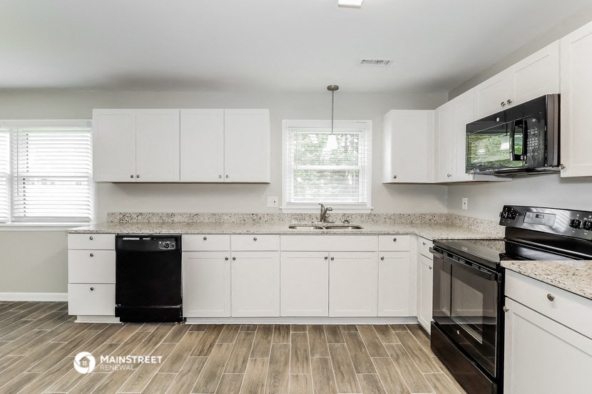 a kitchen with white cabinets and a black stove and a sink