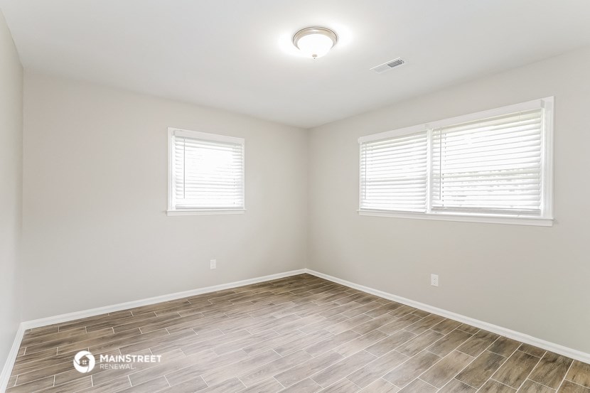 the spacious living room with wood flooring and two windows