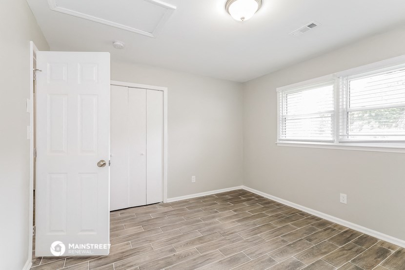 an empty bedroom with a white door and a window