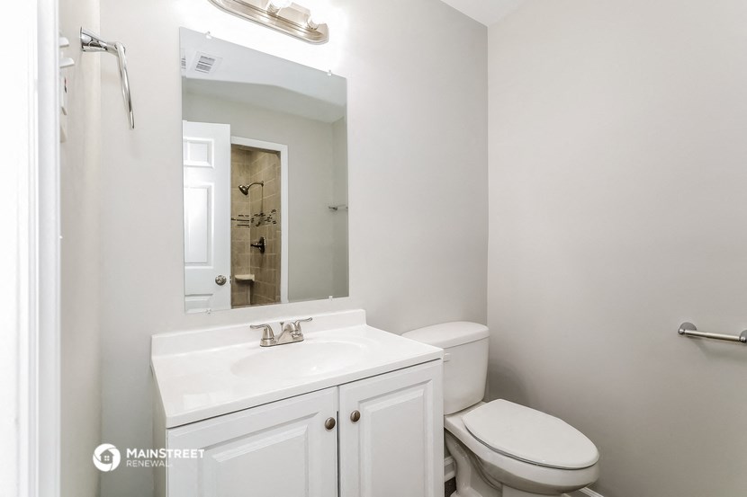a bathroom with a white sink and toilet and a mirror