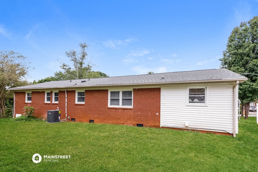 a small brick house with white siding and a yard