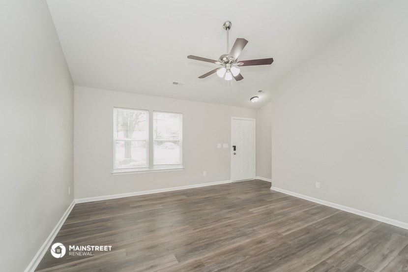 the living room of an empty house with a ceiling fan