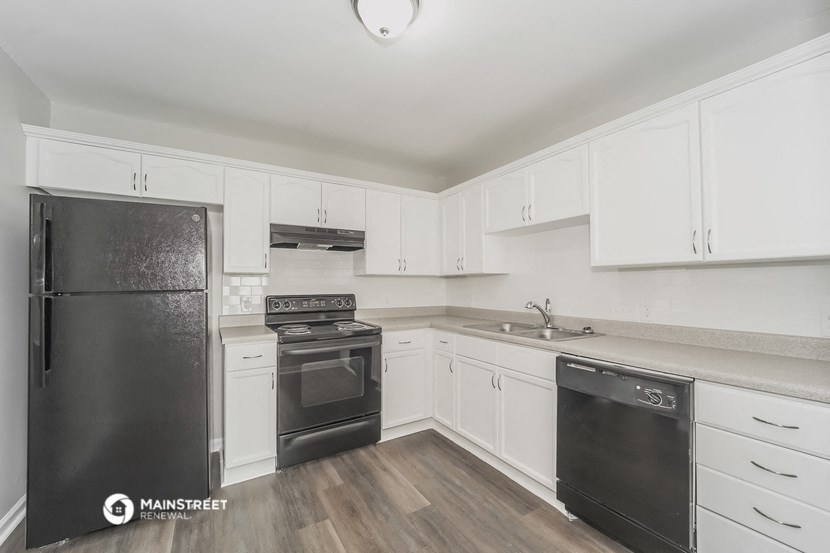 a white kitchen with black appliances and white cabinets