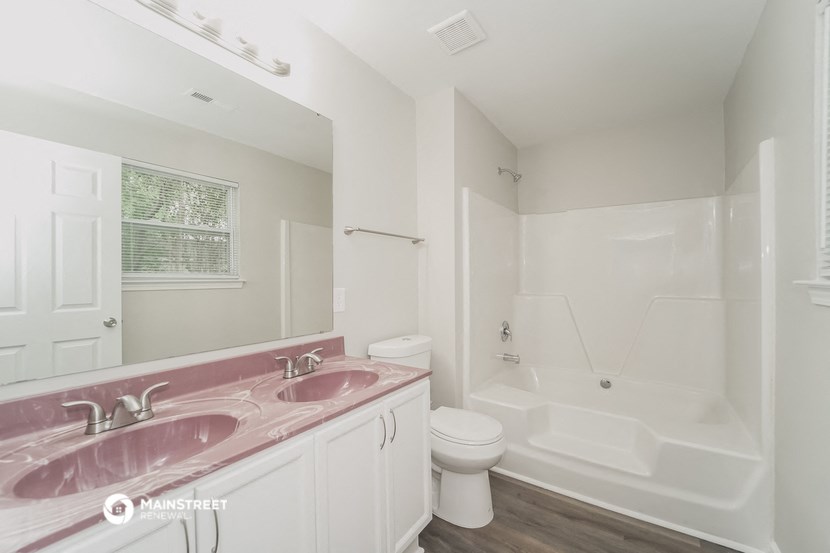 a bathroom with a pink sink and a tub and a toilet