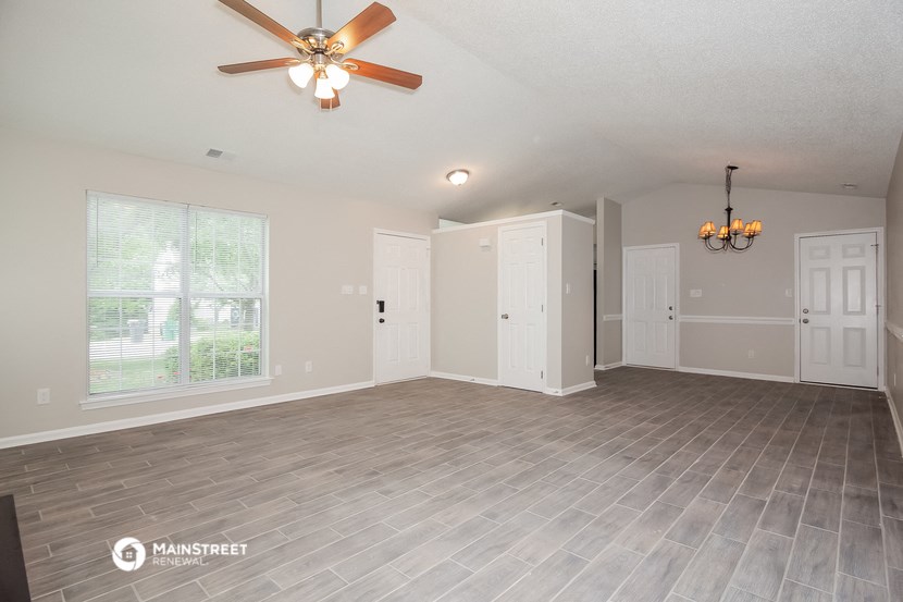 the living room and dining room of an empty house with a ceiling fan