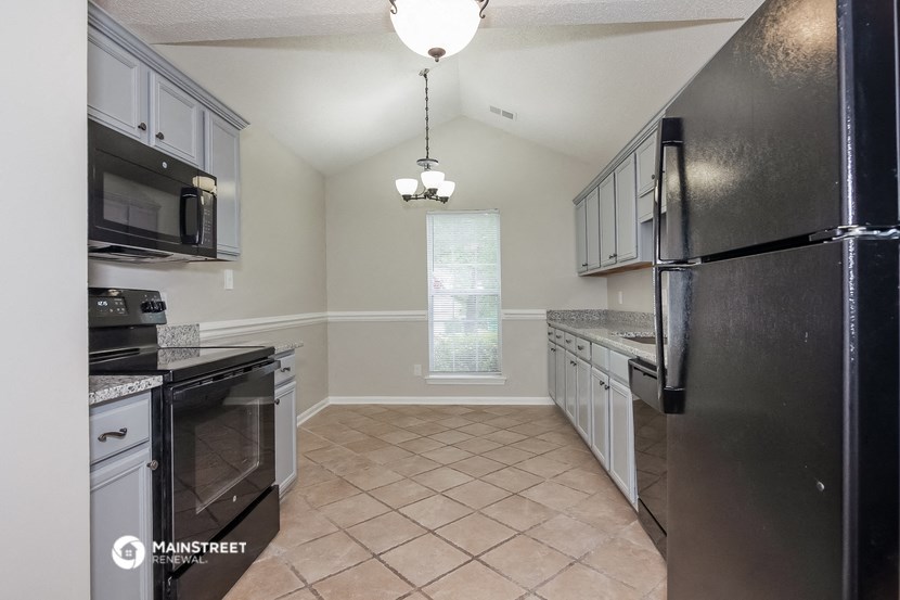 an empty kitchen with black appliances and white cabinets