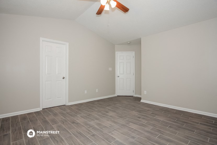 the spacious living room with vinyl flooring and a ceiling fan
