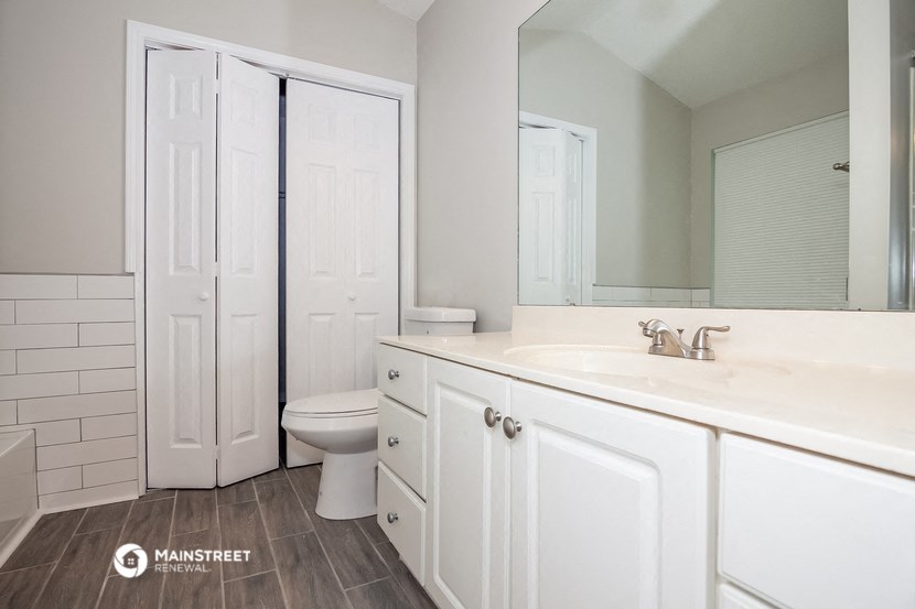 a bathroom with white cabinets and a toilet and a sink