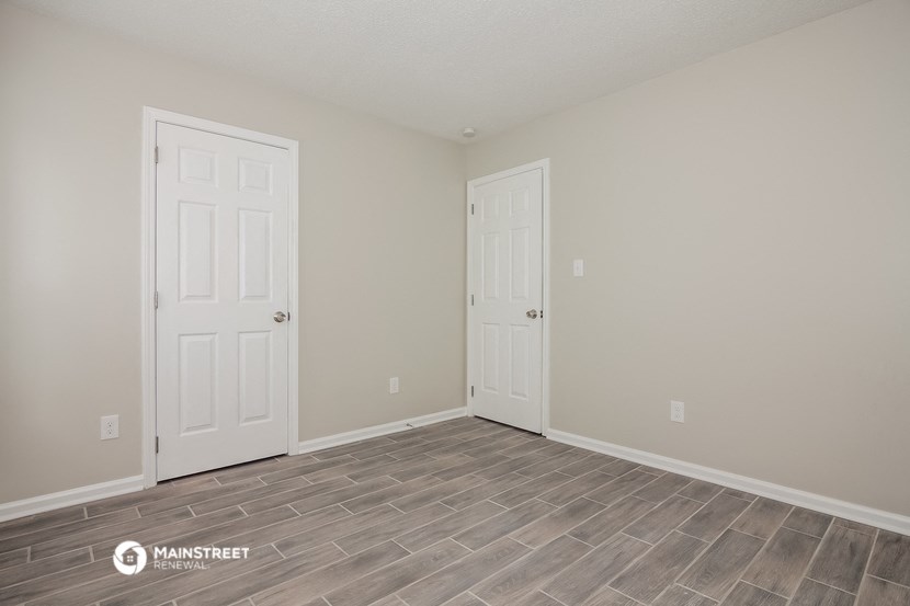 the spacious living room with two doors to the closet