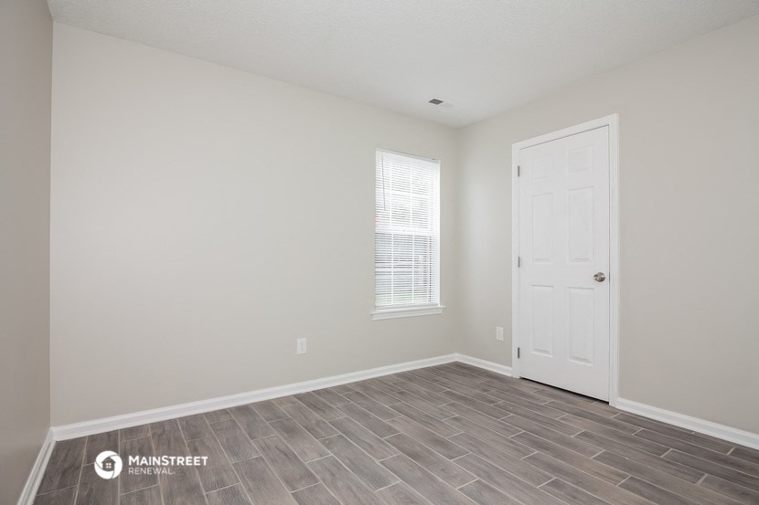 the spacious living room with wood flooring and a white door