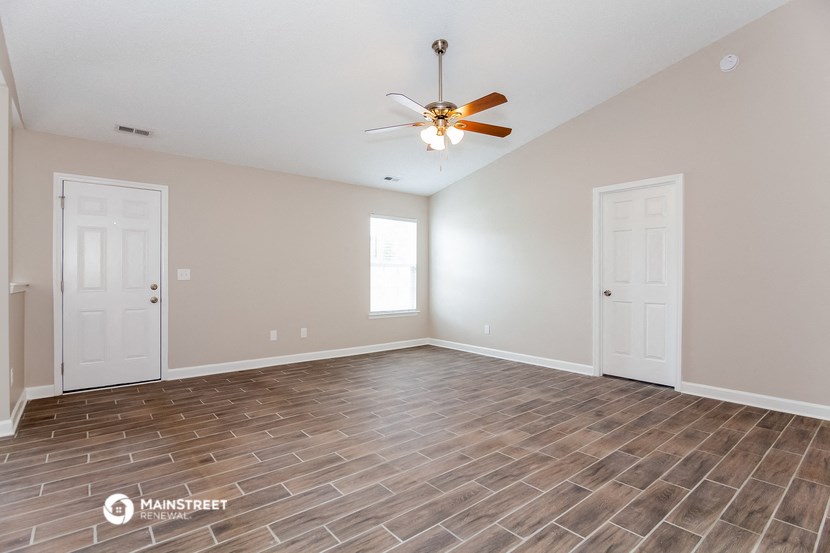the spacious living room with vinyl flooring and a ceiling fan