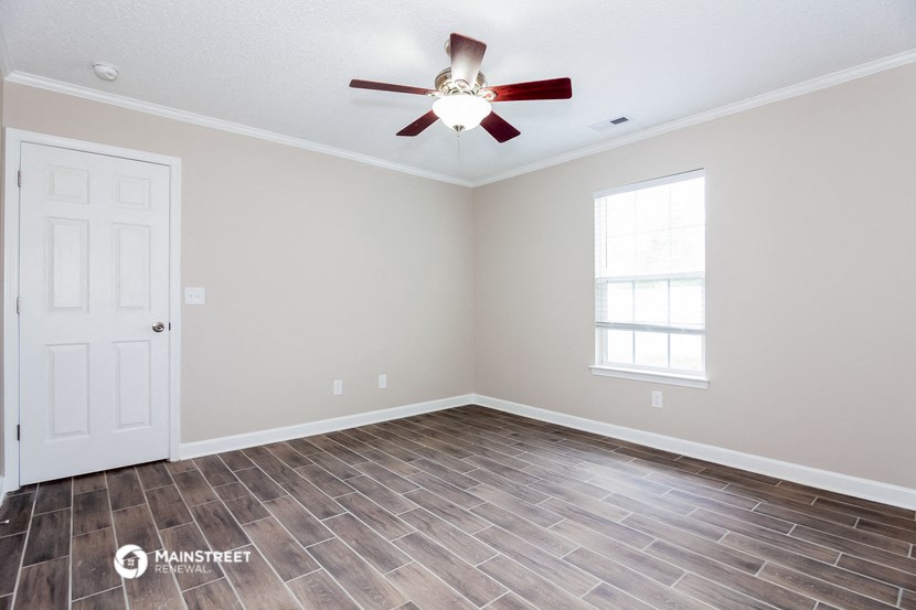 the living room with wood flooring and a ceiling fan