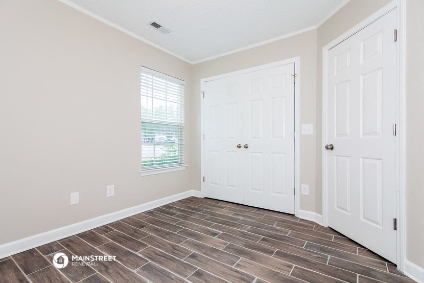 the living room of a new home with white doors and wood tile