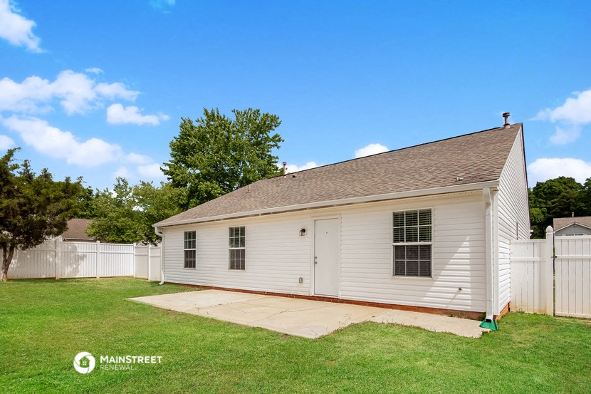 the backyard has a white garage and a grassy area and a white fence
