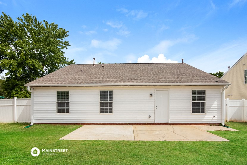 a small white house with a garage in a backyard