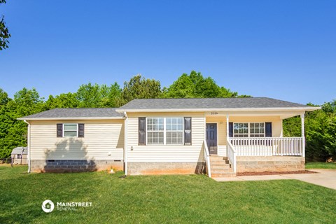 a small white house with a porch and a lawn