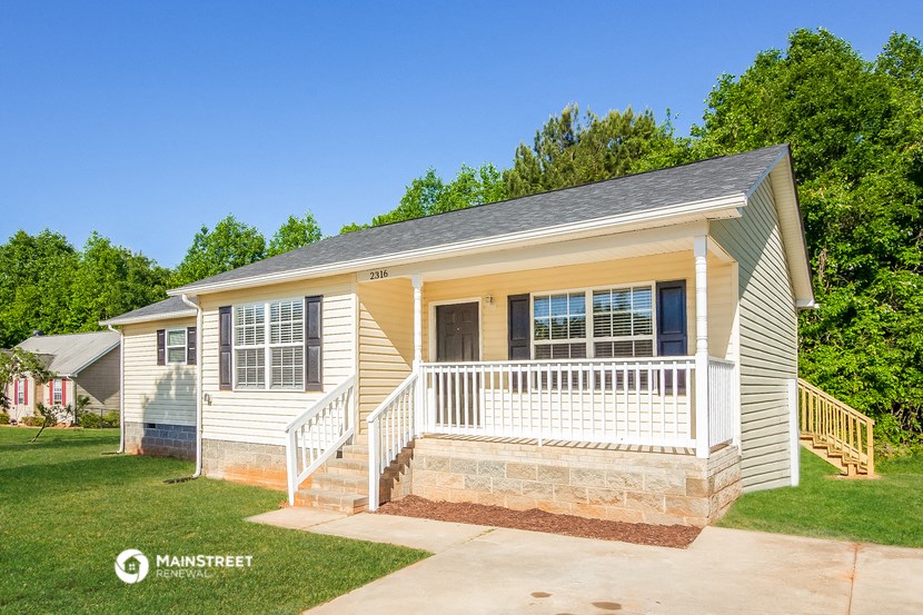 a small yellow and with a porch and a lawn