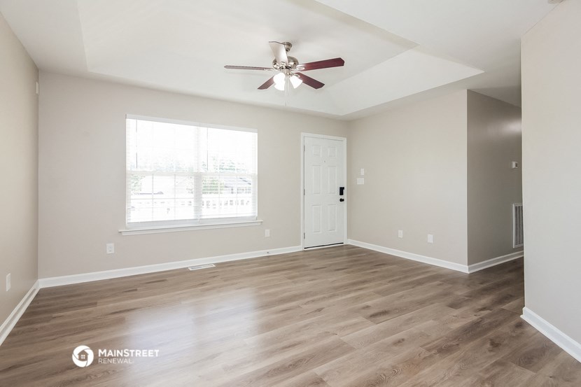 the living room of an empty house with a ceiling fan