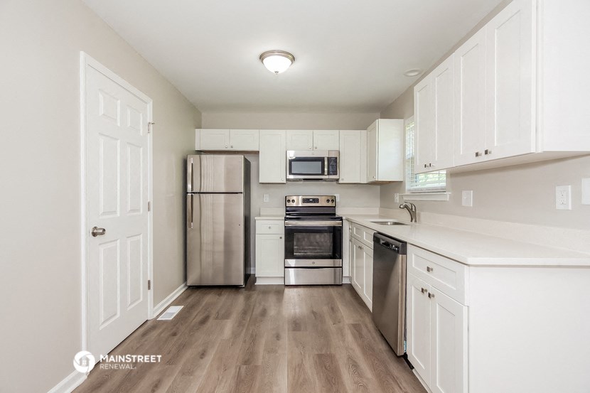 a white kitchen with stainless steel appliances and white cabinets