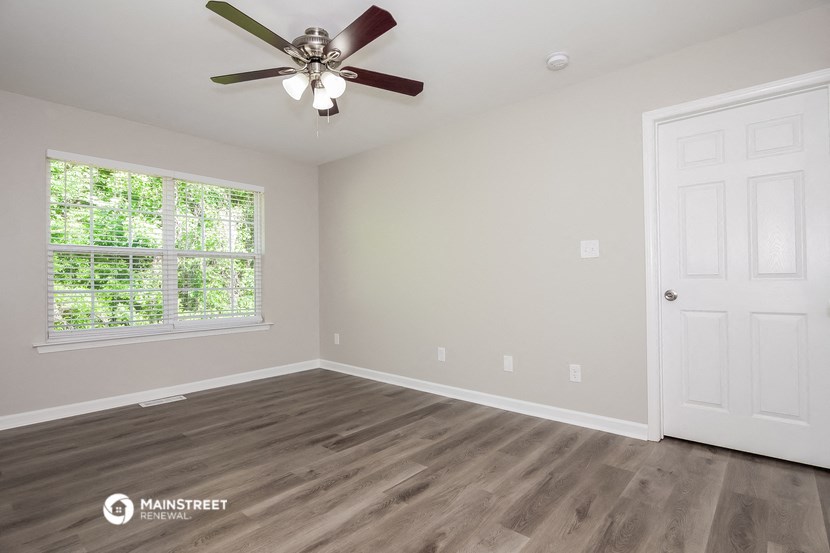 the spacious living room with wood flooring and a ceiling fan