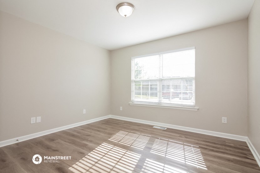 the spacious living room with a large window and wood flooring
