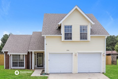 a white house with a garage door and a porch