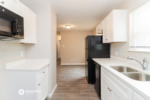 a kitchen with white cabinets and a black refrigerator