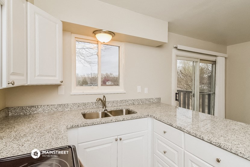 a kitchen with white cabinets and a sink and a window