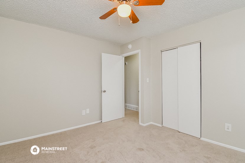 a bedroom with a ceiling fan and a closet