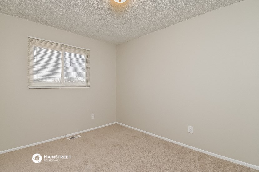a bedroom with a window and beige carpet and white walls