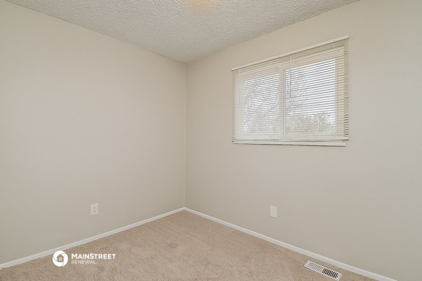 a bedroom with a window and beige walls and carpet
