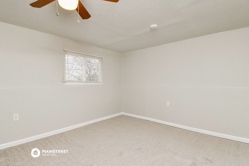 a empty room with a ceiling fan and a window