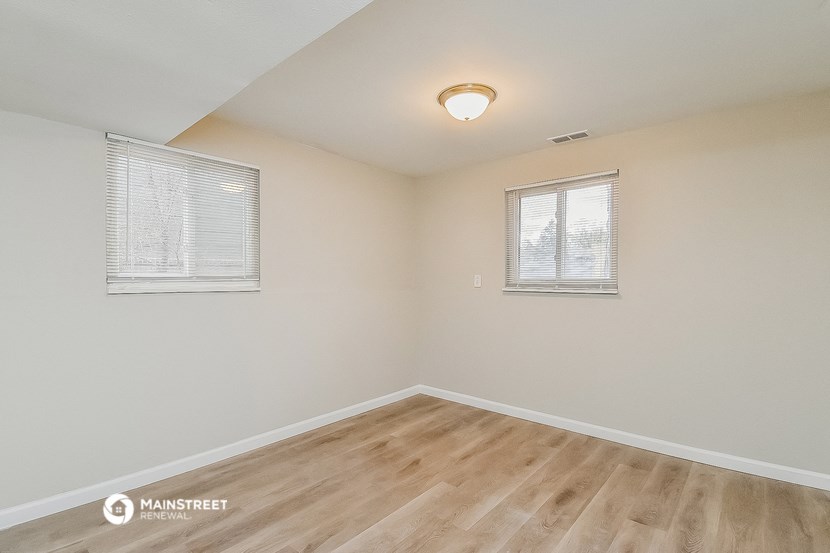the spacious living room with hardwood flooring and two windows