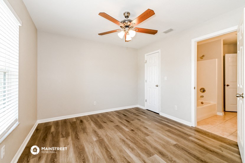 a living room with a ceiling fan and a door to a closet