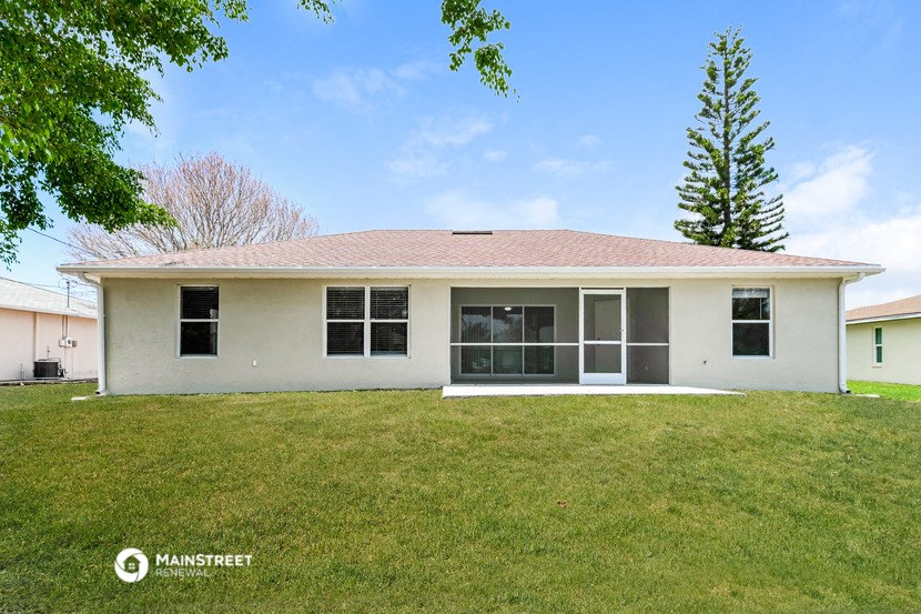a white house with a grassy yard and a tree