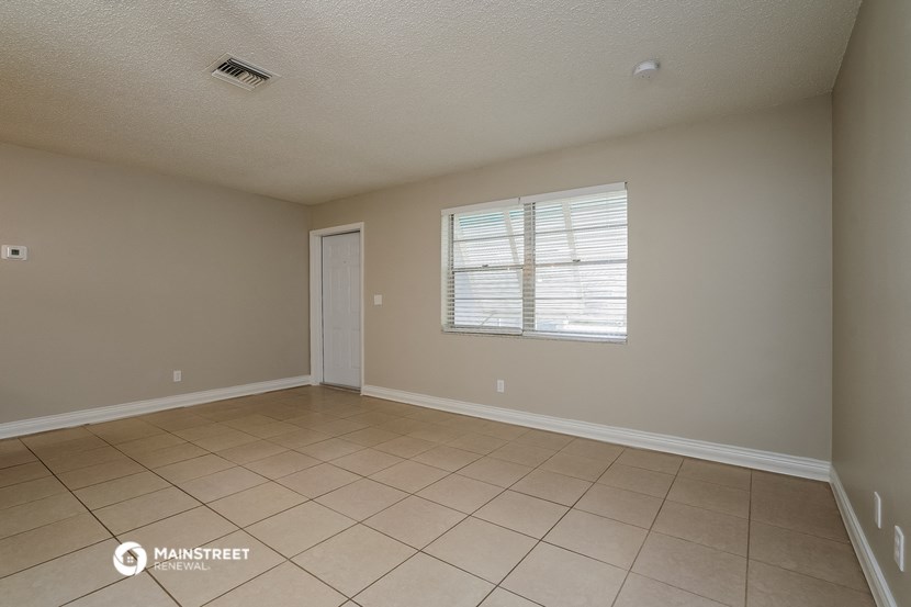 the living room of an empty house with tiled floors and a window