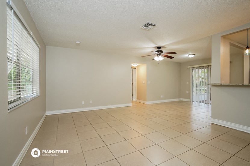 an empty living room with a ceiling fan and tiled floor