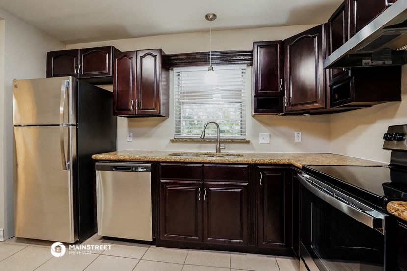 a kitchen with dark wood cabinets and stainless steel appliances