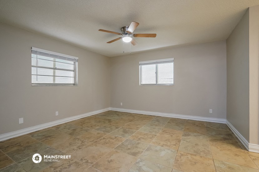 the spacious living room with ceiling fan and tiled floors
