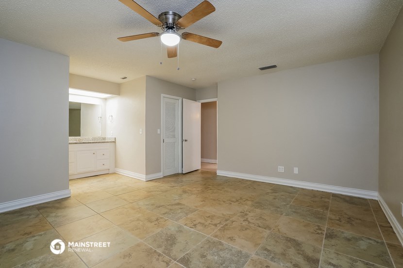the spacious living room with tile flooring and a ceiling fan