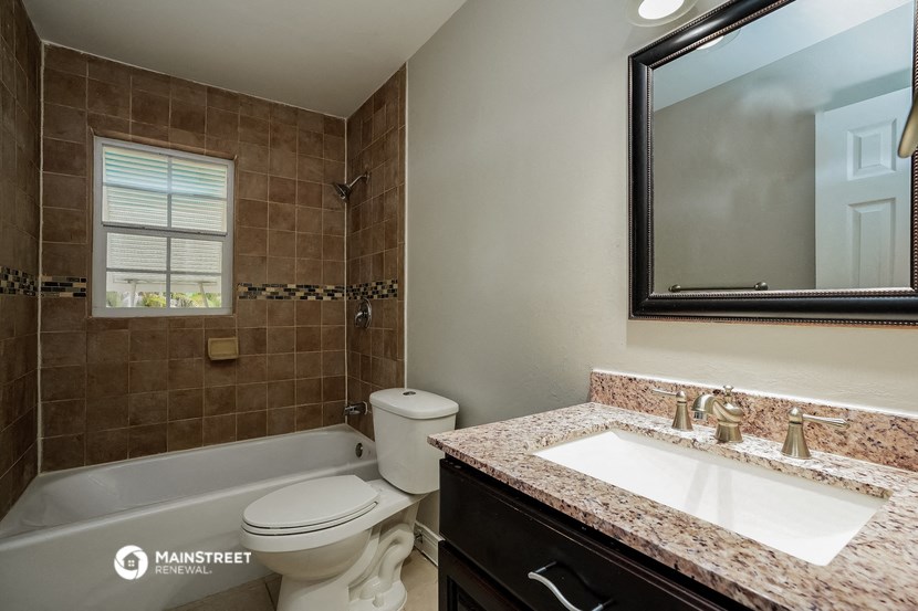 a bathroom with a toilet sink and tub and a mirror