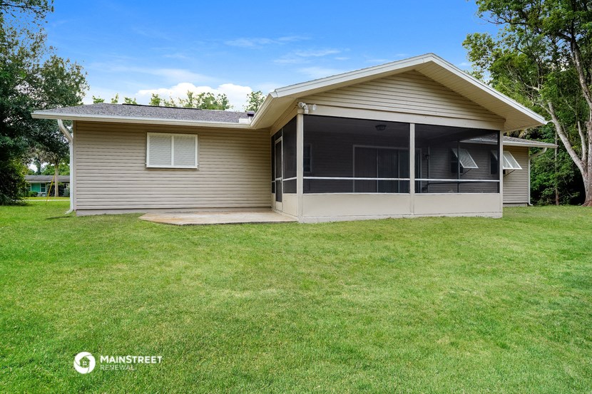 a small tan house with a porch and a lawn