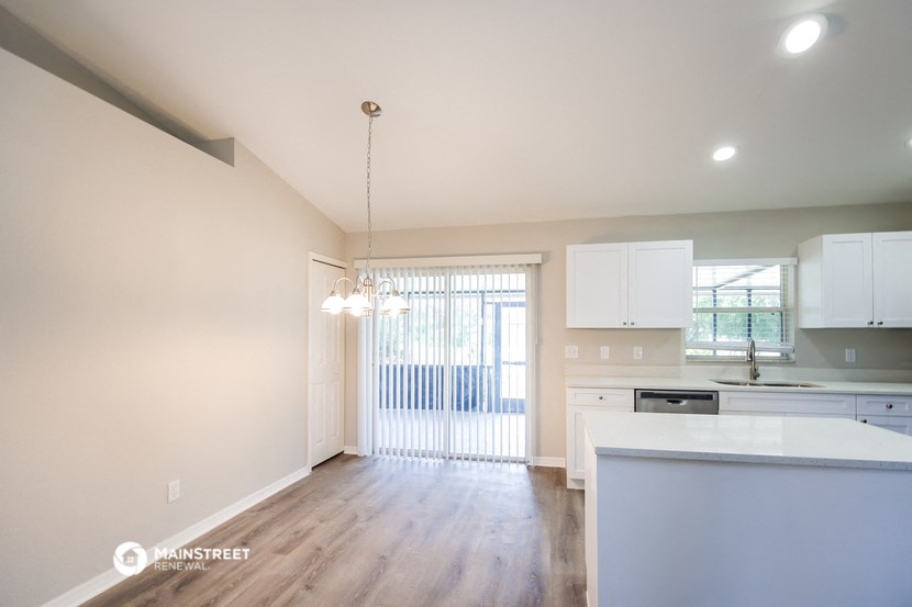 an empty kitchen with white cabinets and a window
