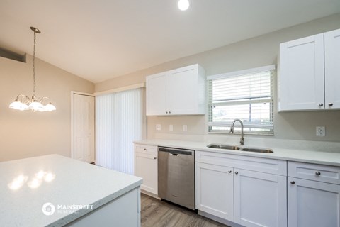 a kitchen with white cabinets and a sink and a window